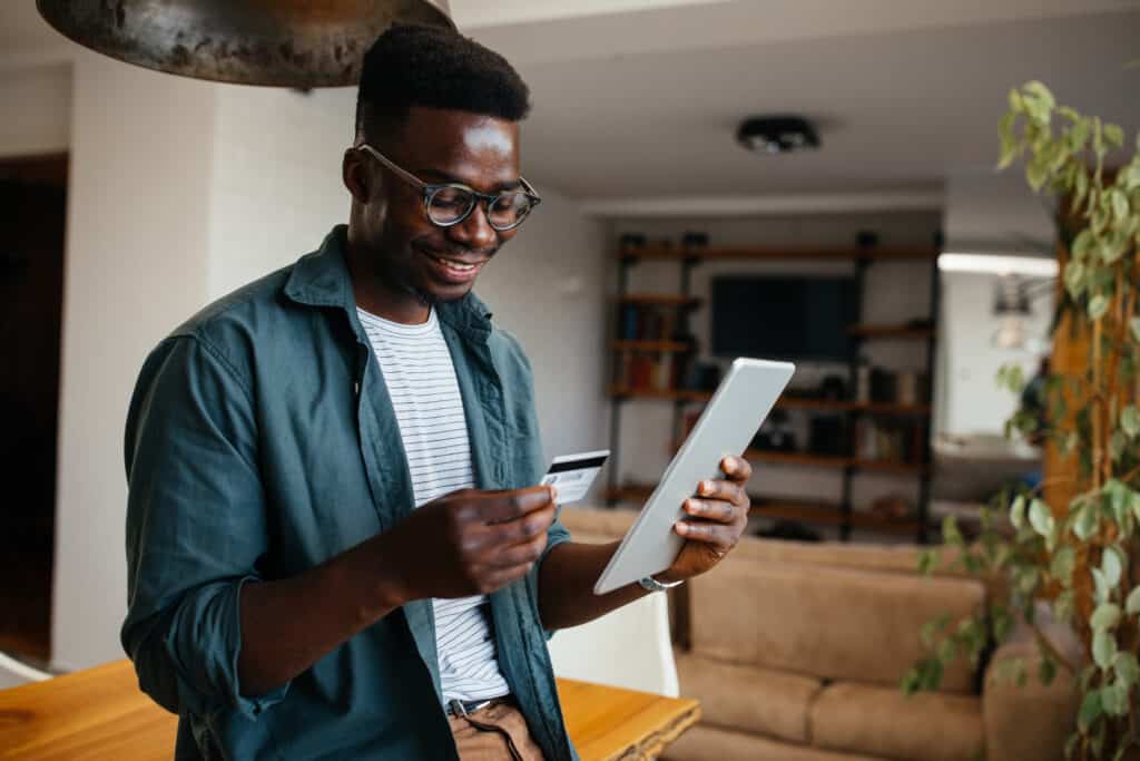 Man using a credit card and tablet to shop online at home