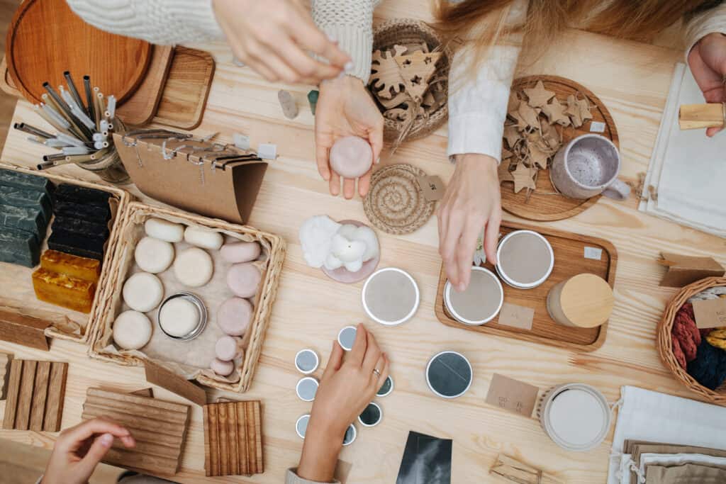 Overhead view of female customer hands picking various cosmetic products to look at.