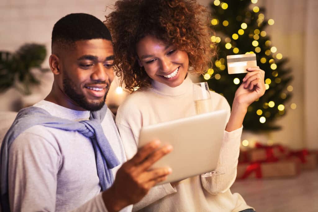 Happy couple buying gifts online, using tablet and credit card